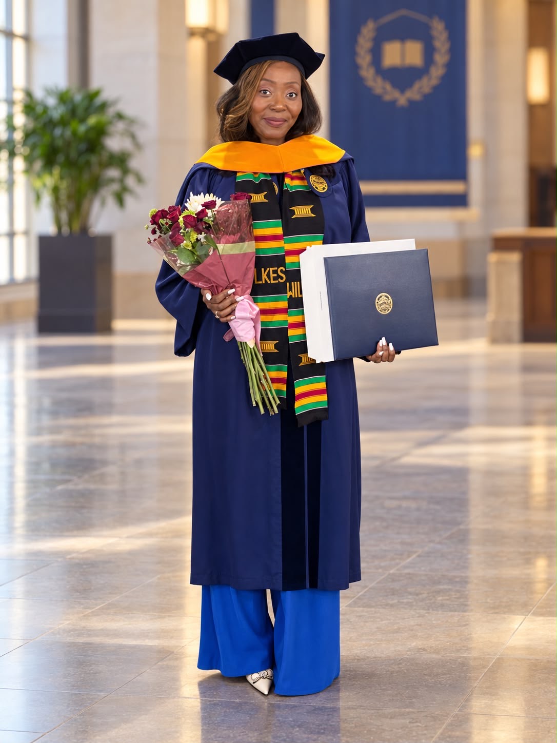 Armelle Tchayep in doctoral regalia holding her Doctor of Nursing Practice diploma